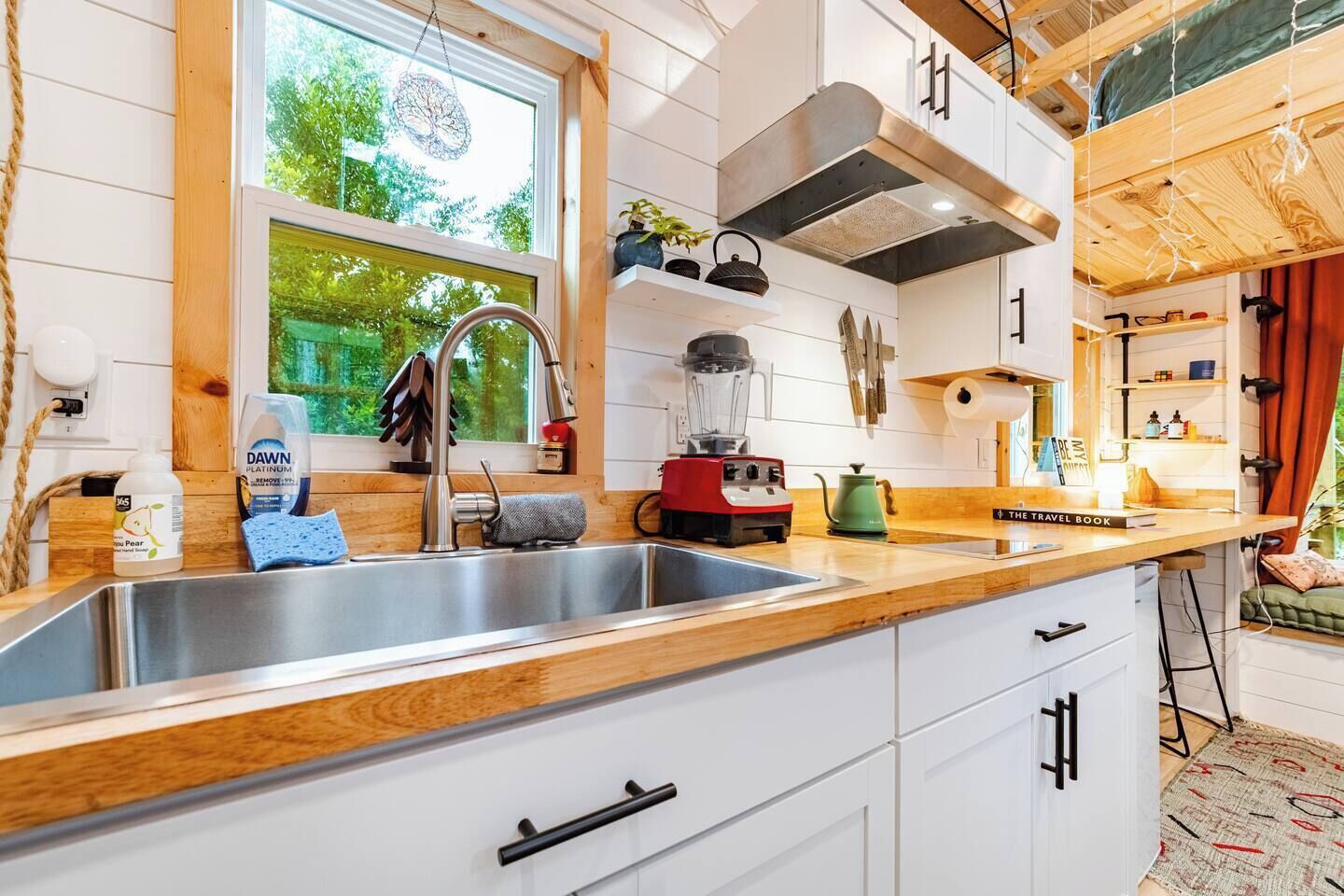A modern kitchen with a stainless steel sink, wooden countertops, and a built-in stove.