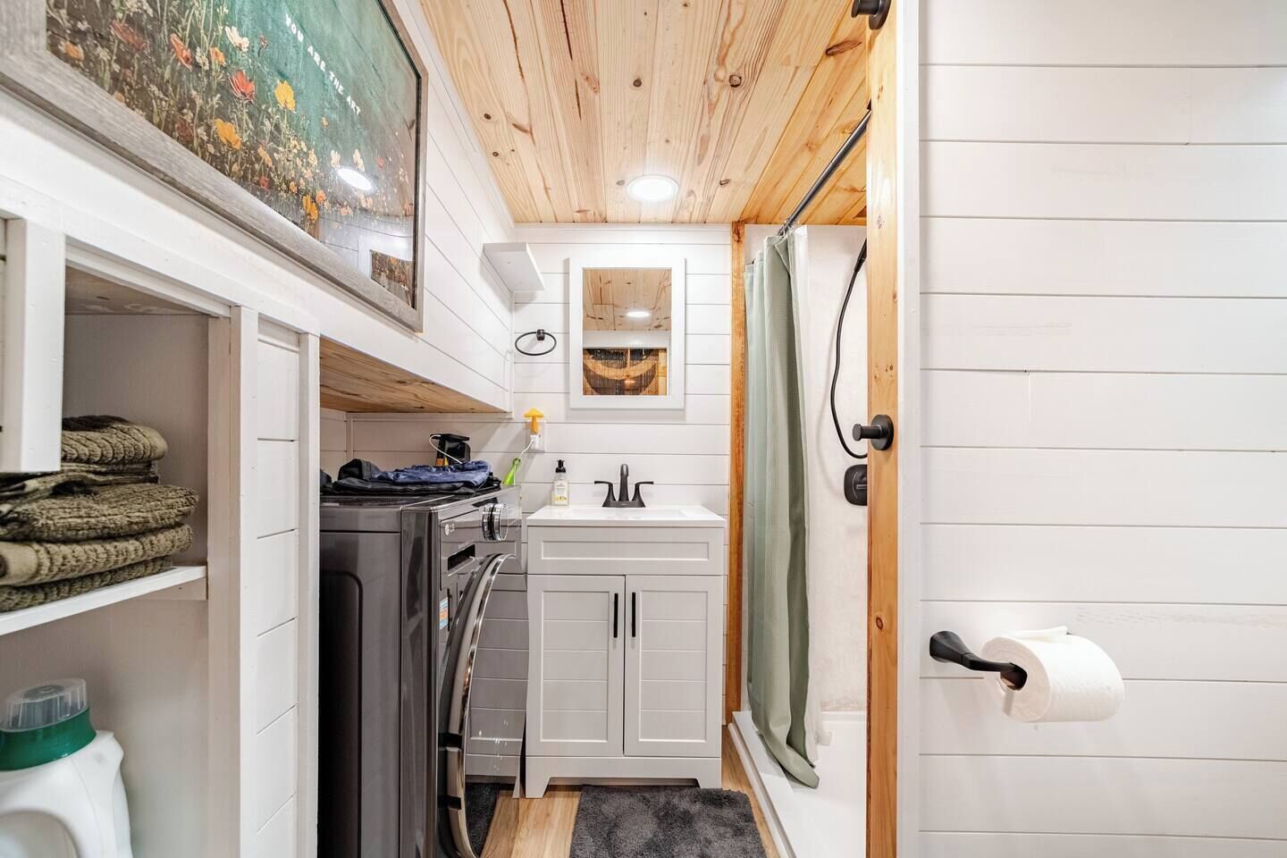 A compact kitchen with a washing machine, a sink, and a small cabinet.