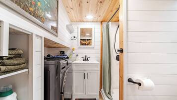 A compact kitchen with a washing machine, a sink, and a small cabinet.