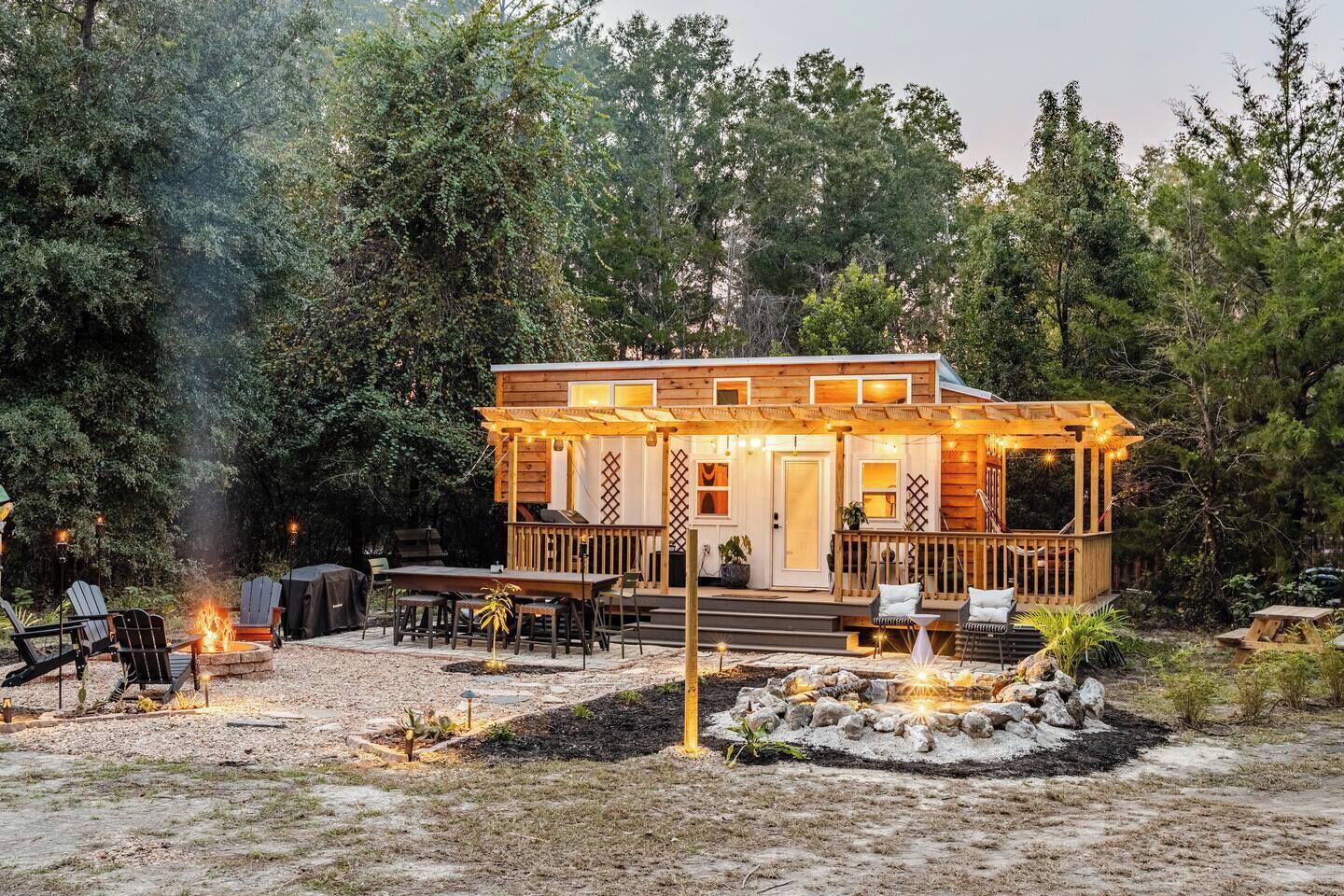 A cabin with a deck, outdoor seating, and a fire pit.