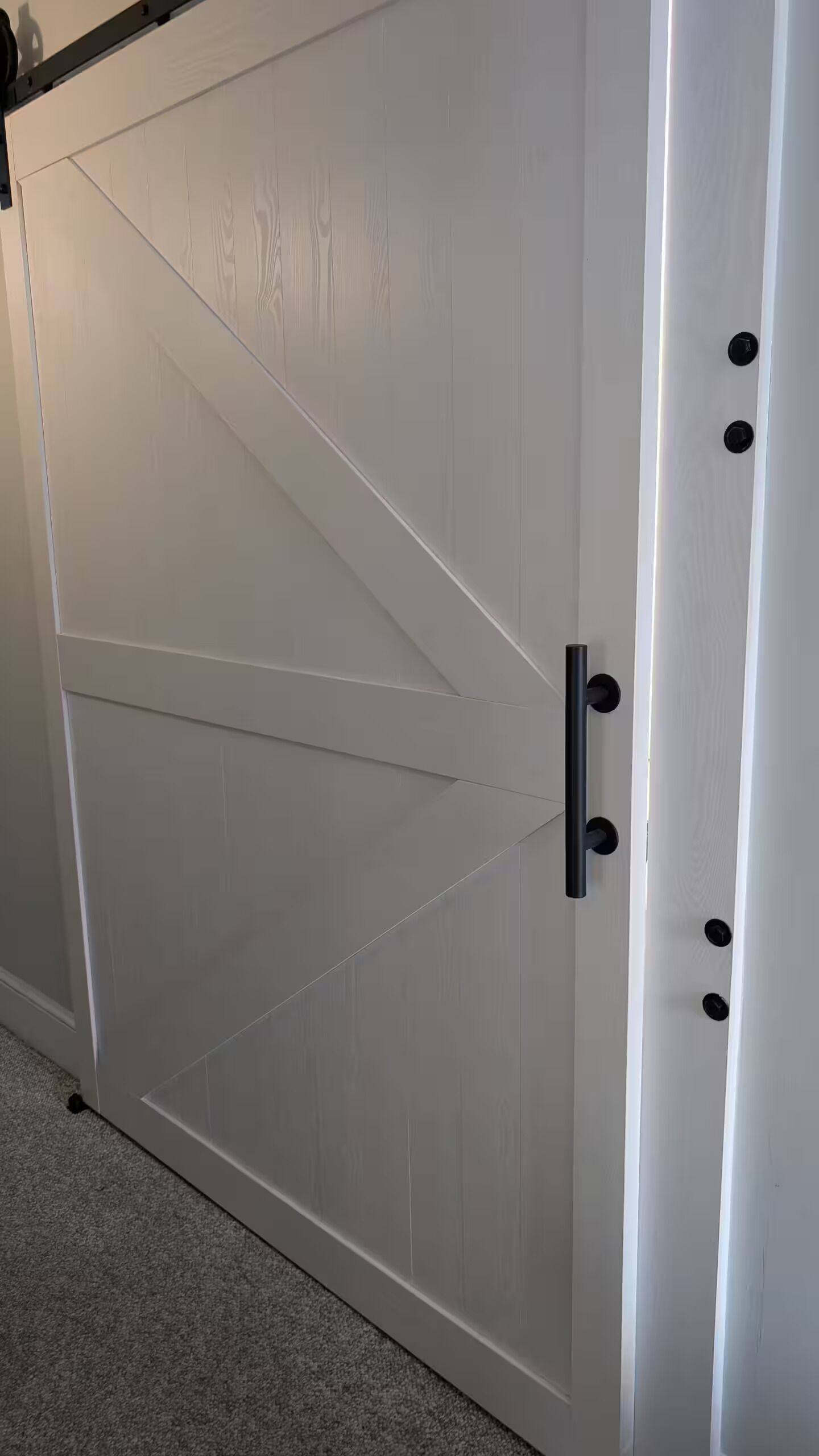 A large, white sliding door with a diagonal design, a black handle, and a visible lock mechanism.