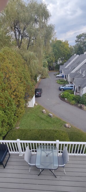 Un barrio residencial con entrada pavimentada, coches aparcados y una hilera de casas con tejados inclinados.