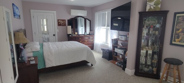 Un dormitorio con cama, cómoda, espejo y aparador con puertas de vidrio.