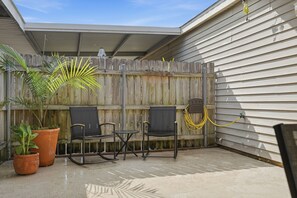 A patio with two chairs, a table, and a potted plant. - A created space that feels like home...The Nest at Woodland (New Iberia)