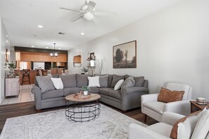 Ein Wohnzimmer mit einem grauen Ecksofa, einem weißen Sessel und einem Couchtisch.