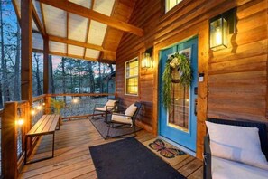 Eine Holzhütte mit Veranda, Sitzgelegenheit und einer Tür mit einem Kranz.