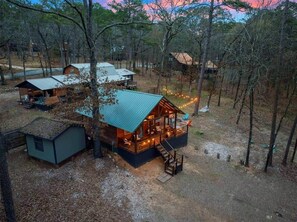 A cabin with a porch and a staircase leading to the entrance, surrounded by trees. - Beaver's Little Lodge I Couples Cabin I Romantic (Hochatown)