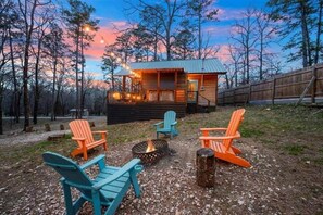 A cabin with a deck, surrounded by trees, and featuring outdoor seating and a fire pit. - Beaver's Little Lodge I Couples Cabin I Romantic (Hochatown)