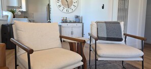 A living room with two armchairs, a clock, a cabinet, and a radiator. - Newly Renovated Coastal Condo with Peekaboo Ocean View (San Clemente)
