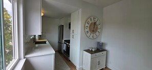 A kitchen with a refrigerator, stove, and a clock on the wall. - Newly Renovated Coastal Condo with Peekaboo Ocean View (San Clemente)