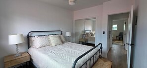 A bedroom with a bed, bedside lamps, a mirror, and a wardrobe. - Newly Renovated Coastal Condo with Peekaboo Ocean View (San Clemente)
