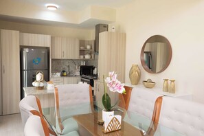 A modern kitchen with a dining area, including a refrigerator, stove, and cabinets. - NOK Cozy 2BR Stay in Vistacana Punta Cana (Punta Cana)