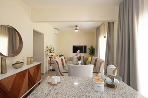 A modern dining area with a granite table, white ceramic dishes, and a wooden cabinet. - NOK Cozy 2BR Stay in Vistacana Punta Cana (Punta Cana)