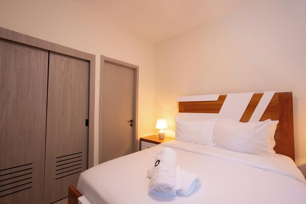 A hotel room with a bed, a nightstand with a lamp, and two wardrobes. - NOK Cozy 2BR Stay in Vistacana Punta Cana (Punta Cana)