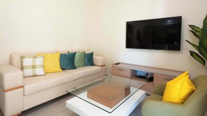 Ein modernes Wohnzimmer mit einer Couch, einem Couchtisch, einem Fernseher und einer Pflanze.