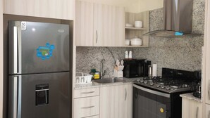 Eine moderne Küche mit einem Edelstahl-Kühlschrank, einem Gasherd und Arbeitsplatten aus Granit.