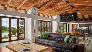 A spacious living area with a leather sofa, wooden coffee table, and a large sliding glass door leading to a balcony. - Beautiful luxury house in Guacalito de la Isla, Casa Kidd (Tola)