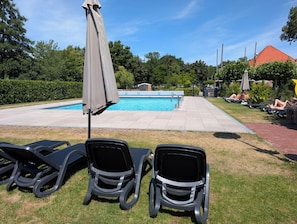 A swimming pool area with lounge chairs and umbrellas.