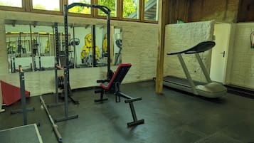 Uma academia com equipamentos de exercícios, um espelho e uma esteira.