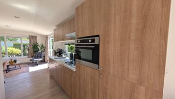 Una cocina moderna con armarios de madera, electrodomésticos de acero inoxidable y vistas al exterior.