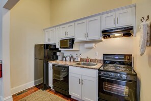A kitchen with white cabinets, a stainless steel refrigerator, a microwave, a dishwasher, a sink, and a stove. - Luxury MidCentury Modern Condo; Heart of Downtown Augusta (Augusta)