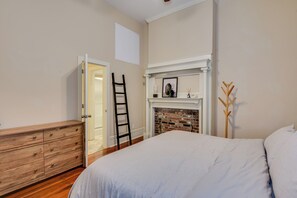 A bedroom with a wooden dresser, a ladder, a fireplace, and a bed. - Luxury MidCentury Modern Condo; Heart of Downtown Augusta (Augusta)