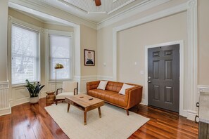 A living room with a brown leather sofa, a wooden coffee table, a white rug, and a potted plant. - Luxury MidCentury Modern Condo; Heart of Downtown Augusta (Augusta)