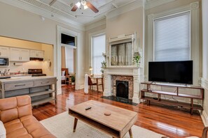 A spacious living room with a fireplace, a television, and a kitchen area with cabinets and a stove. - Luxury MidCentury Modern Condo; Heart of Downtown Augusta (Augusta)