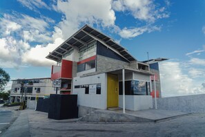 A modern building with a flat roof, large windows, and a yellow door.