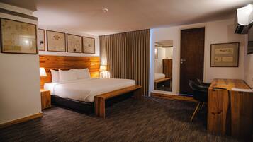 Ein Hotelzimmer mit Bett, Nachttisch, Lampe und Schreibtisch mit Stuhl.