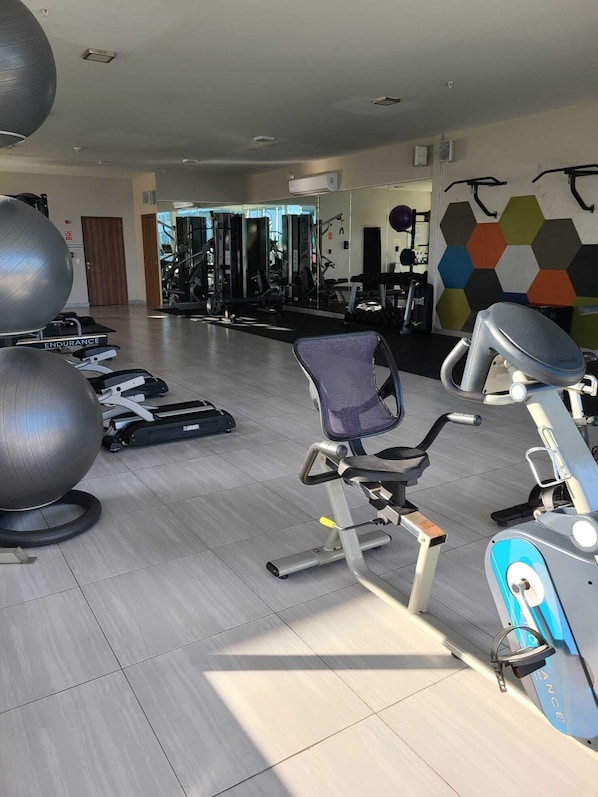 Un gimnasio con equipamiento de ejercicio, un espejo grande y un diseño de baldosas hexagonales.