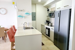 A modern kitchen with a stainless steel refrigerator, a microwave, and a sink. - Wake Up to the Ocean – Beautiful Beachfront Condo (Nueva Gorgona)