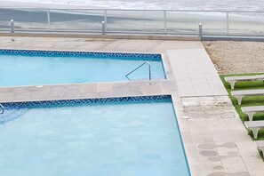 Una piscina con borde de azulejos y escalera de metal.
