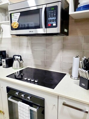 Una cocina equipada con microondas, estufa, horno y diversos utensilios.