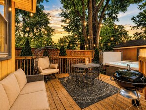 A deck with outdoor furniture, a hot tub, and string lights. - Casa Newburg | Hot Tub • Game Garage • Fenced Yard (Louisville)