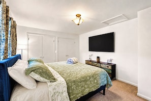 Ein Schlafzimmer mit einem Bett, einem Schminktisch, einem Fernseher und einer Deckenleuchte.