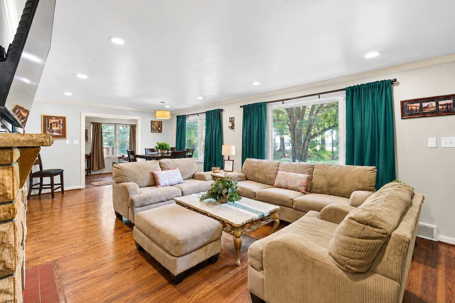 A spacious living room with a large sofa set, a coffee table, and a dining area with a table and chairs.