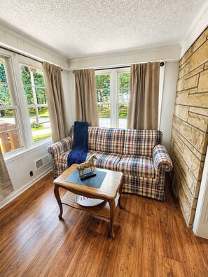 A cozy room with a plaid sofa, a blue chair, and a wooden coffee table. - Casa Newburg | Hot Tub • Game Garage • Fenced Yard (Louisville)