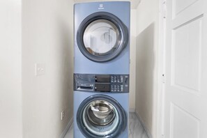 Eine Waschmaschine an der Wand, mit Bedienfeld und Tür, frontal abgebildet.