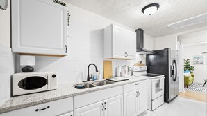 Een moderne keuken met witte kastjes, een roestvrijstalen koelkast en een magnetron.
