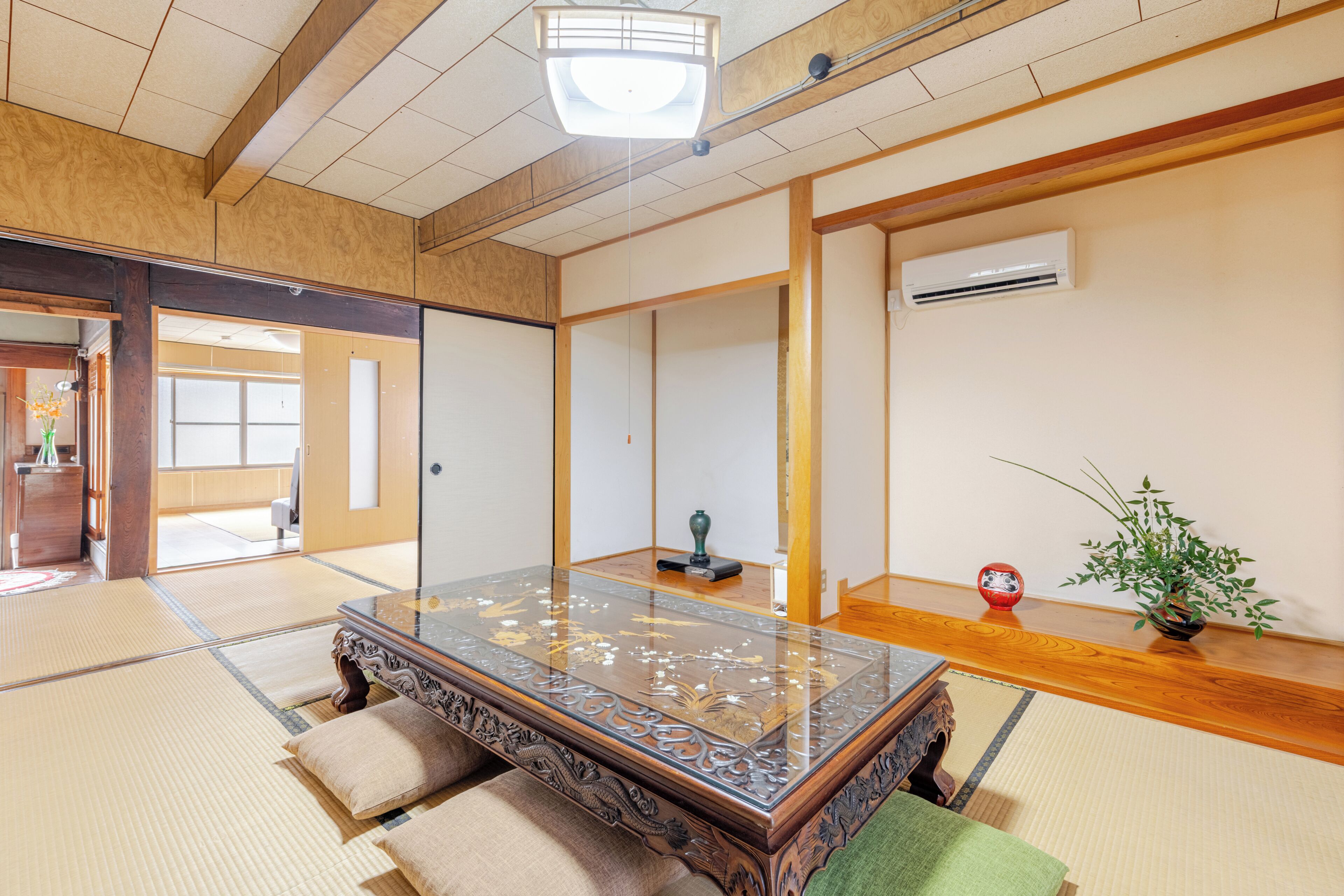 A traditional Japanese room with tatami flooring, a low wooden table, sliding doors, and a ceiling fan.