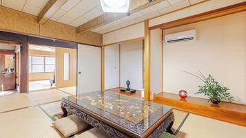 A traditional Japanese room with tatami flooring, a low wooden table, sliding doors, and a ceiling fan.