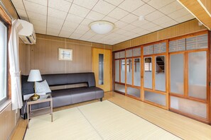 A room with a sofa, a small table with a lamp, a traditional sliding door, and a ceiling with a grid pattern.