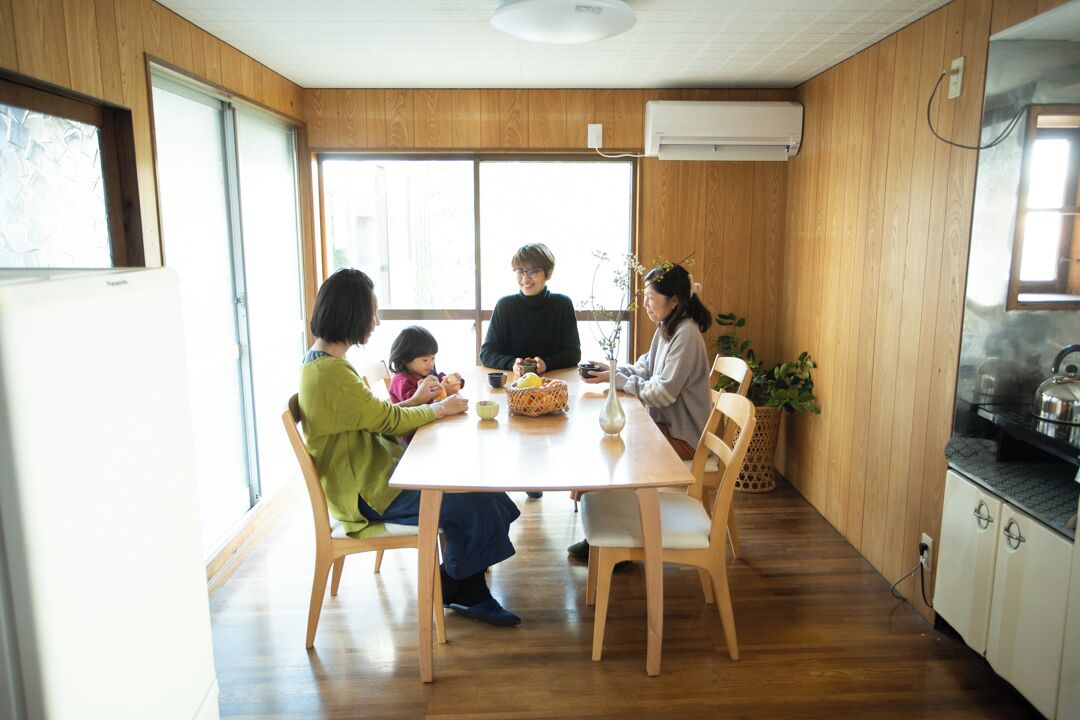 A family dining at a wooden table with a view of the outdoors.