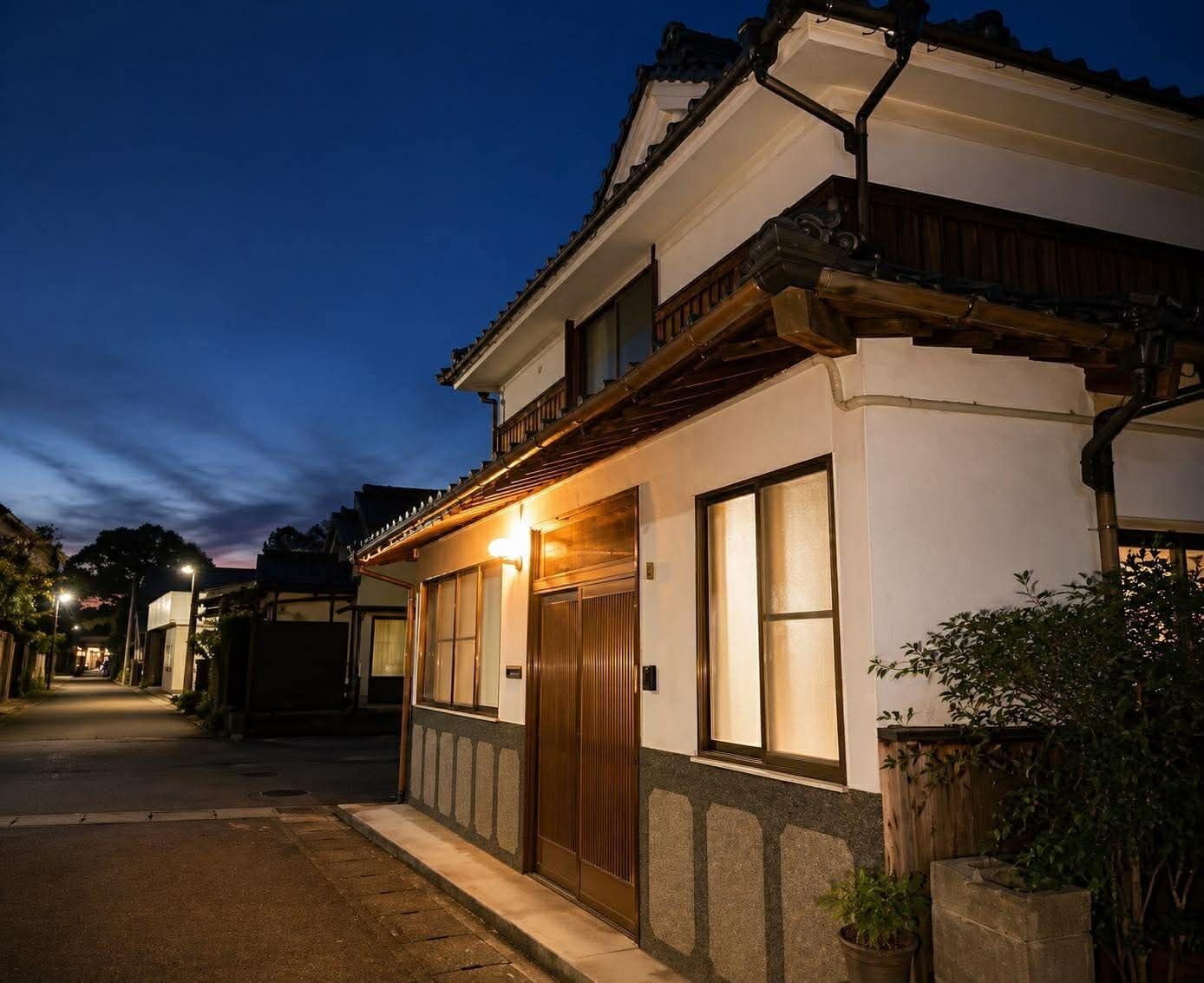 A traditional building with a wooden balcony, large windows, and a well-lit entrance.