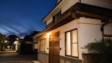 A traditional building with a wooden balcony, large windows, and a well-lit entrance.