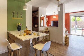 A modern kitchen with a marble countertop, two bar stools, and a dining table. - Villa Masté - Piscine - Clim - Verdon (Aups)