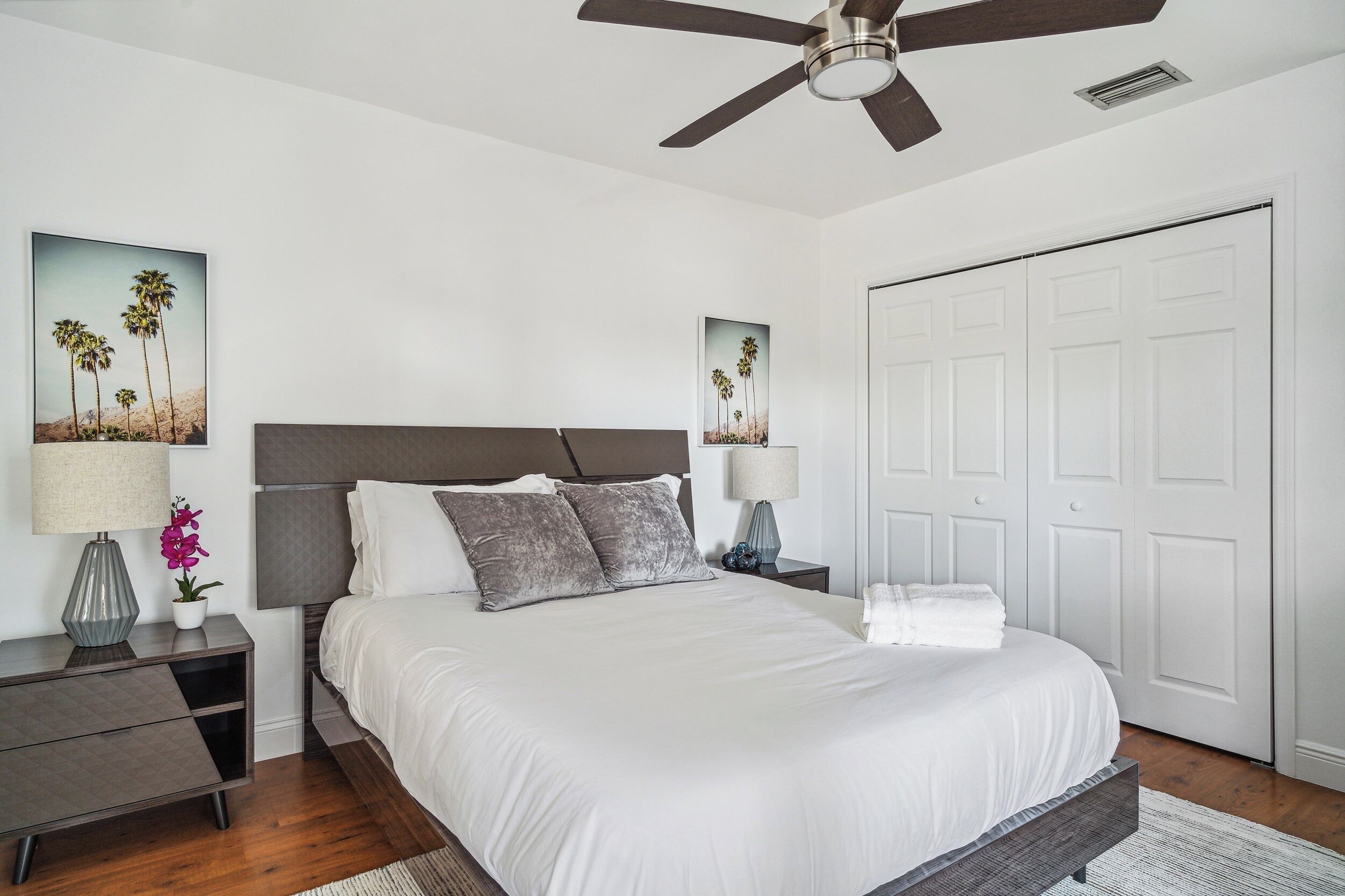 A bedroom with a bed, nightstands, a ceiling fan, and a door.