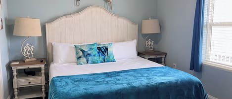 A bedroom with a bed, two nightstands, a lamp, and a window with curtains.