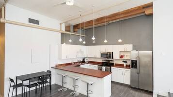 A modern kitchen with white cabinets, a central island, stainless steel appliances, and pendant lighting.